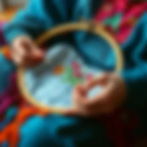 A person stitching with a hoop in their lap, surrounded by colorful threads and fabric. The focus is on the hoop holding the fabric steady while they work on a design.