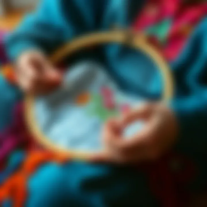 A person stitching with a hoop in their lap, surrounded by colorful threads and fabric. The focus is on the hoop holding the fabric steady while they work on a design.