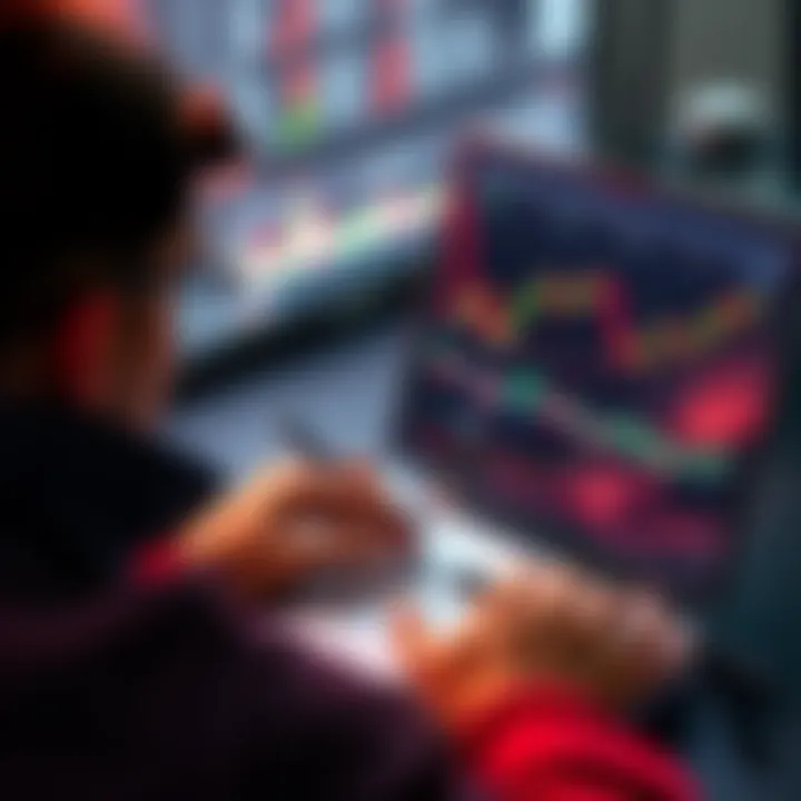 Person Checking Price Charts Individual focused on a price chart displayed on a laptop screen, analyzing cryptocurrency trends. A notebook and pen are nearby for note-taking.